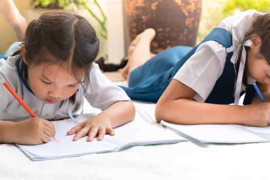 two sister girl writes to writing-books. The decision of lessons. girl lay down drawing the picture