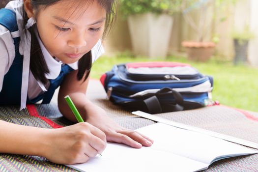 little girl writes to writing-books. The decision of lessons. girl lay down drawing the picture