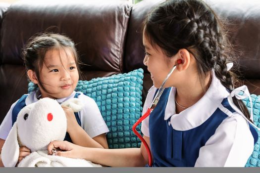 two little girl are smiling and playing doctor with stethoscope. Kid and health care concept.