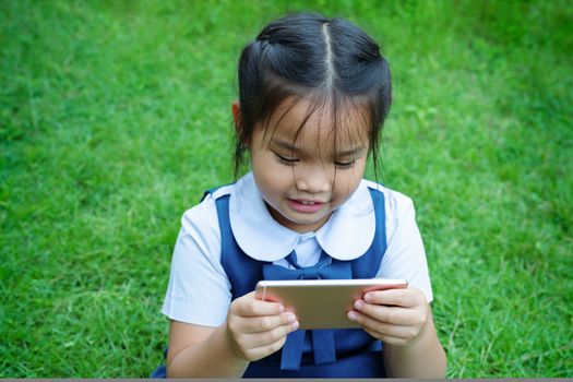 cute little girls playing internet with mobile smartphone on grass