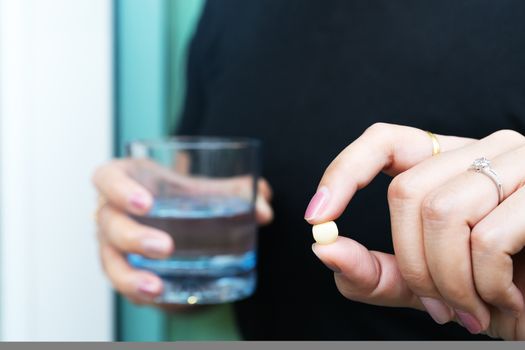medicine, health care and people concept - close up a pill on woman hand