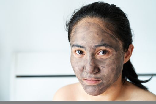 asia woman applied charcoal mask on her bare face
