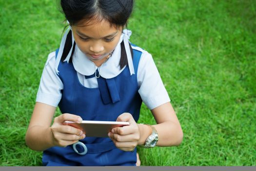 cute little girls playing internet with mobile smartphone on grass