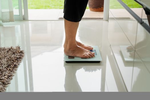 old woman standing on weight scale in living room