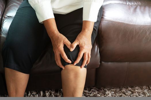 senior woman suffering from knee pain at home, health problem concept