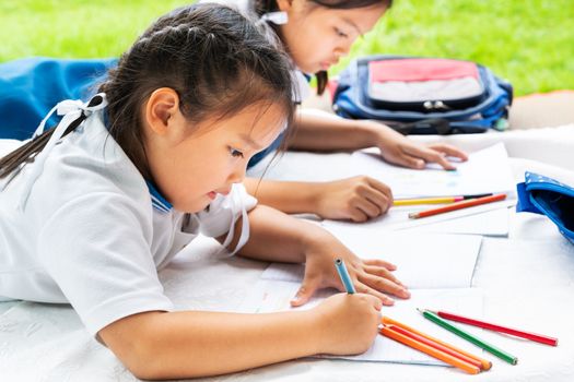 two sister girl writes to writing-books. The decision of lessons. girl lay down drawing the picture