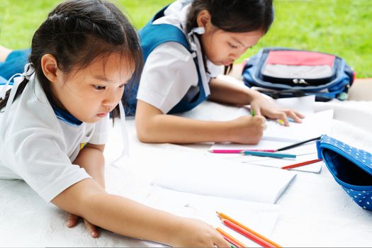 two sister girl writes to writing-books. The decision of lessons. girl lay down drawing the picture