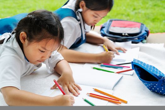 two sister girl writes to writing-books. The decision of lessons. girl lay down drawing the picture