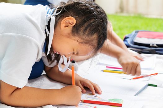 cute little girl writes to writing-books. The decision of lessons. girl lay down drawing the picture