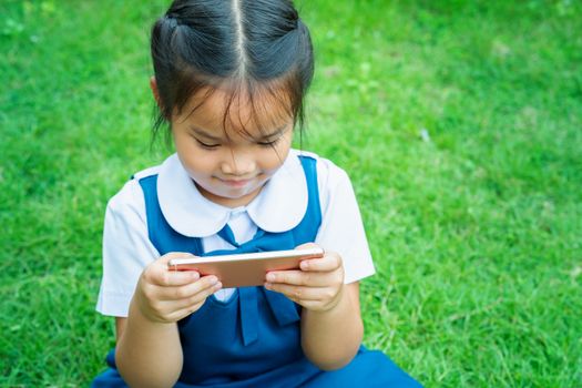 cute little girls playing internet with mobile smartphone on grass