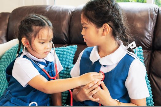 two little girl are smiling and playing doctor with stethoscope. Kid and health care concept.