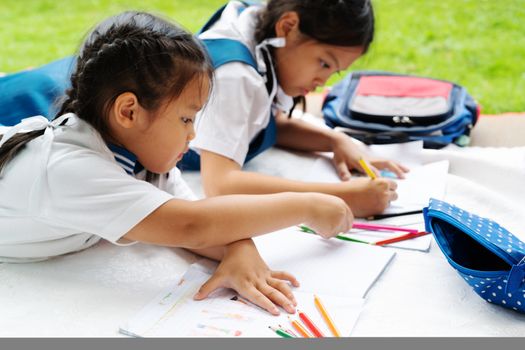 two sister girl writes to writing-books. The decision of lessons. girl lay down drawing the picture