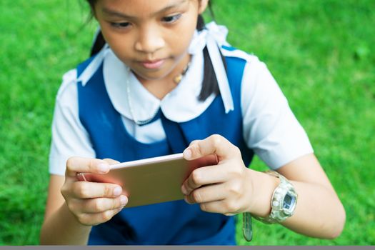 cute little girls playing internet with mobile smartphone on grass