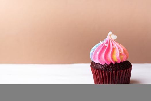 Cute little white heart on rainbow cream cupcake, sweet dessert concept
