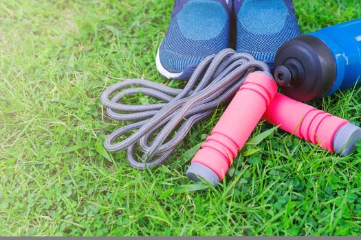 Jump rope, Running shoes, and drink bottle on grass background