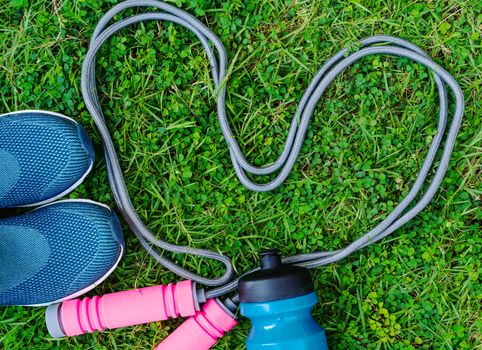 Jump rope, Running shoes, and drink bottle on grass background