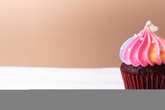 Cute little white heart on rainbow cream cupcake, sweet dessert concept, close up