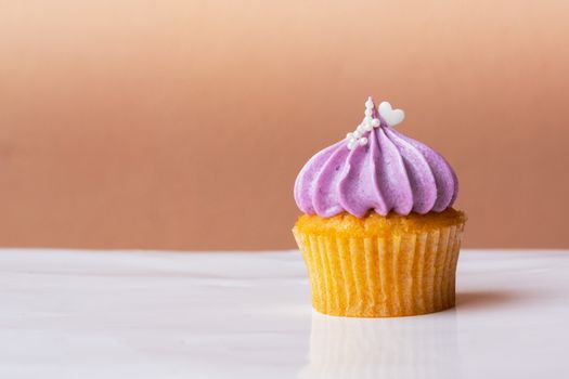 cute cupcake with small white heart on purple cream on pink background