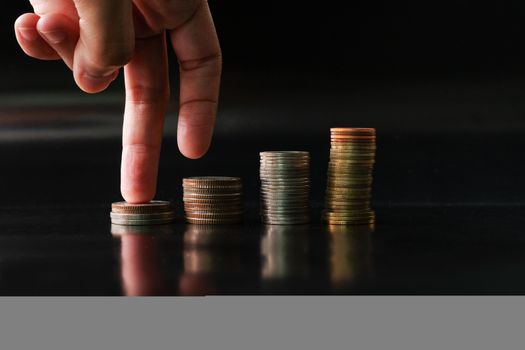 fingers step upward on stack of coins on black background concept business finance growing