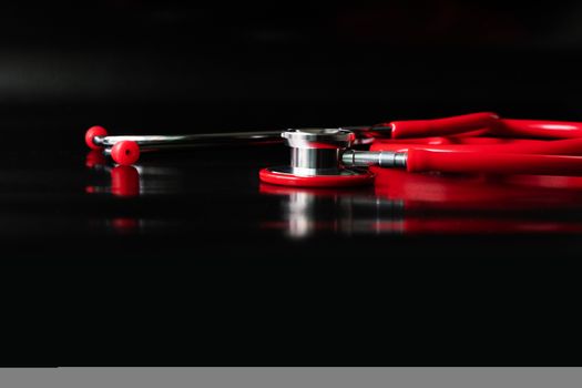 red stethoscope on black background. Healthcare and medicine concept