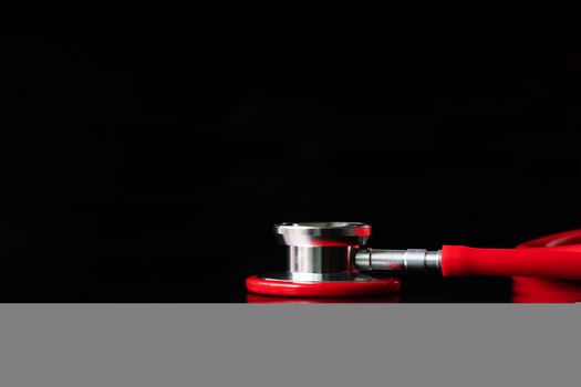 red stethoscope on black background. Healthcare and medicine concept