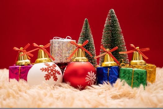 Christmas background concept. Christmas gift box and tree with golden bells, pine cones, red and white ball on red background