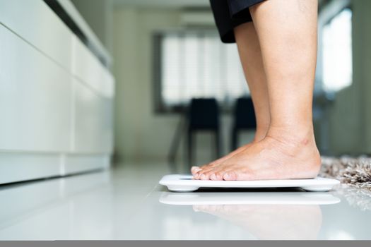 old woman standing on weight scale in living room