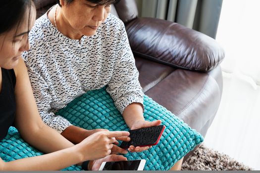 Adult woman and daughter using smartphone with blank screen. Woman pointing on mobile phone display