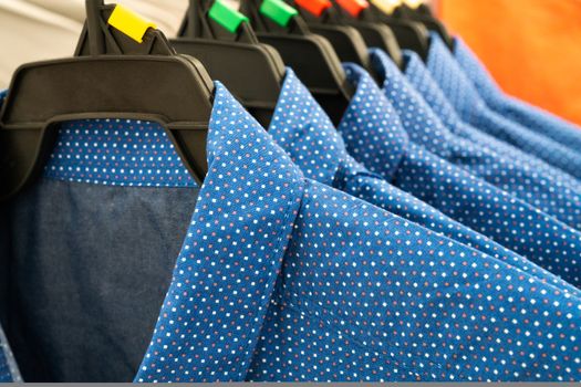 male cloth, row of blue man shirts on hanger in closet