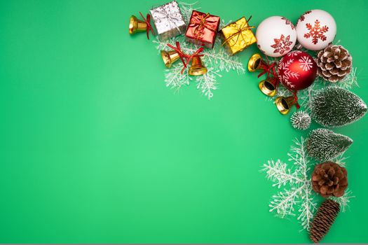 Christmas background concept. Christmas gift box and tree with golden bells, pine cones, red and white ball on green background
