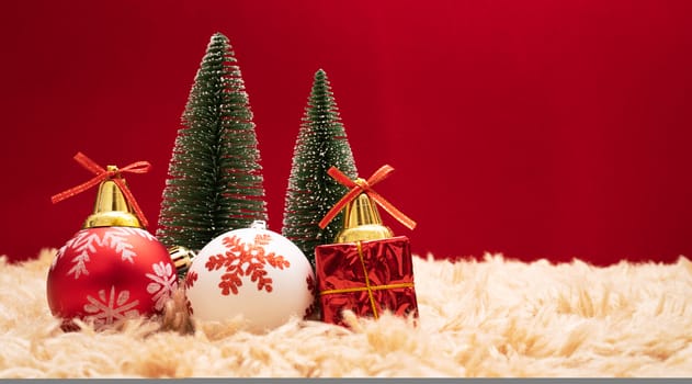 Christmas background concept. Christmas gift box and tree with golden bells, pine cones, red and white ball on red background