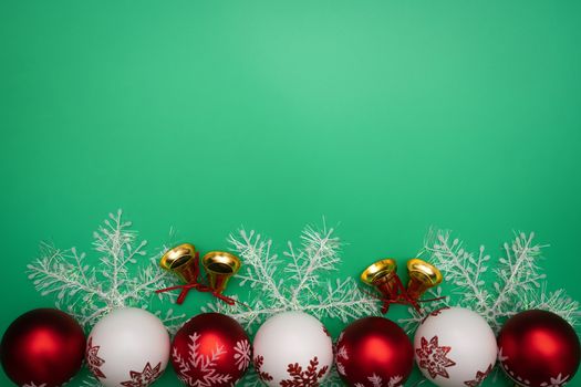 Christmas composition. Christmas gift, bell and ball on green background. Flat lay, top view, copy space