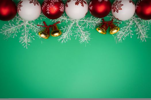 Christmas composition. Christmas gift, bell and ball on green background. Flat lay, top view, copy space