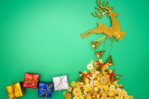 Christmas gloden reindeer composition. Christmas gift, gold reindeer and bell on green background. Flat lay, top view, copy space