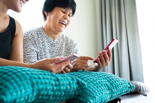 Adult woman and daughter using smartphone. Woman smiling look at mobile phone display