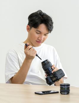 An Asian photographer is cleaning the camera and lens with a air blower camera cleaning for shooting fashion models in the studio.