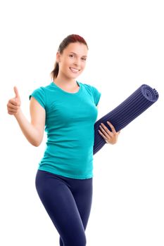 Beautiful smiling young girl in sportswear holding a yoga mat giving thumbs up, isolated on white background. Healthy lifestyle concept. Fitness and yoga concept.