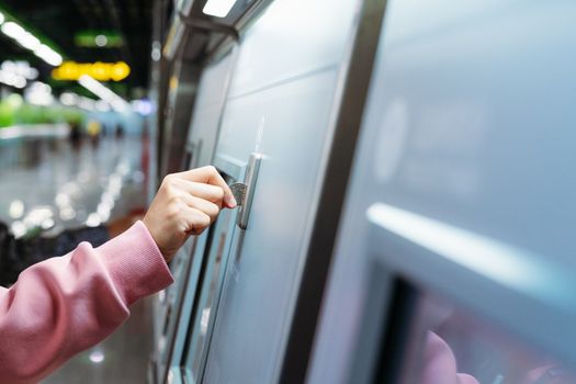 Woman hand inserts coin to buy subway train ticket in machine. Transportation concept