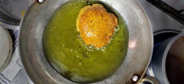 Deep fried Indian bread called Puri in a cooking pan with vegetable oil