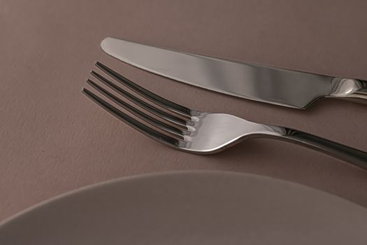Empty plate and cutlery as mockup set on brown background, top tableware for chef table decor and menu branding design