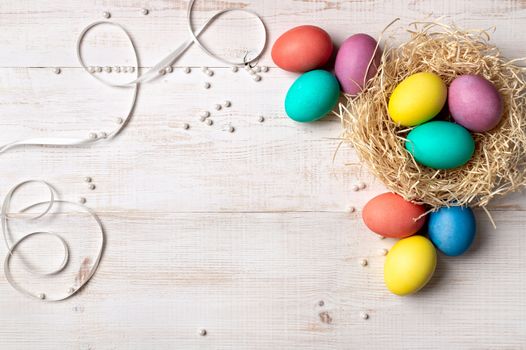 Easter concept. Colorful eggs on white wooden background with copy space for text or design. Top down view or flat lay