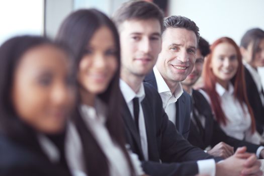 Successful business people group in a row sitting at the desk at meeting and smiling
