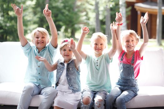 Image of happy children friends raising arms and screaming in joy