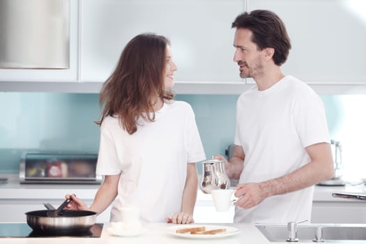 Couple cooking breakfast together in kitchen