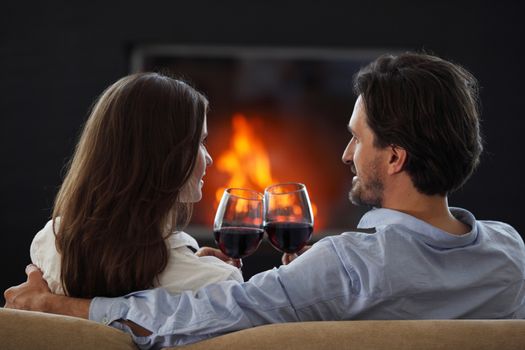 Close up of young couple drinking wine in front of an open wood fire at Valentines day love passion concept