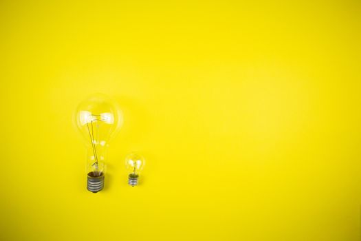 Two bulbs - large and small. Yellow background, tehnology