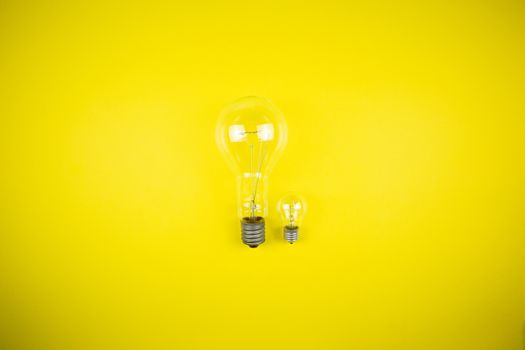 Two bulbs - large and small. Yellow background, tehnology
