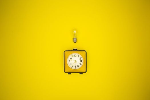 Yellow alarm clock and light bulb