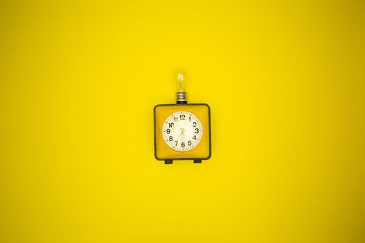 Yellow alarm clock and light bulb