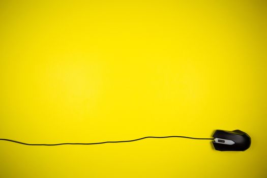 Computer yellow mouse with a long wire on a yellow background